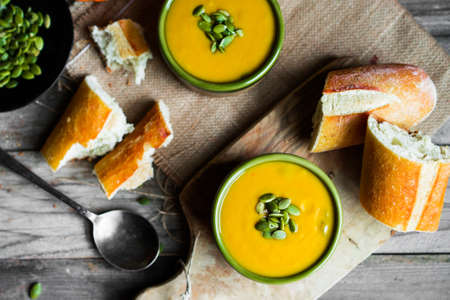Creamy pumpkin soup with seeds on wooden backgroundの写真素材