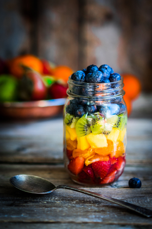 Colorful fruit salad in a jar on rustic wooden backgroundの写真素材