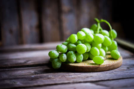 Vine of green grapes on rustic wooden backgroundの写真素材