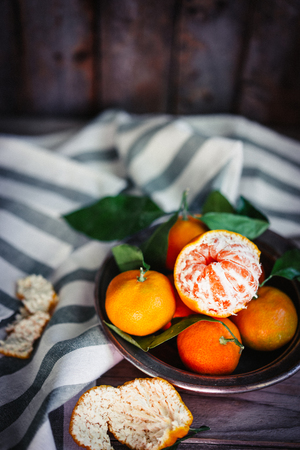 Tangerines with leaves on rustic wooden backgroundの写真素材