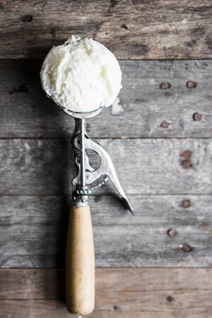 Scoop of vanilla ice-cream on rustic wooden backgroundの写真素材