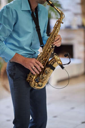 A male saxophonist in a blue shirt plays the saxophone.の写真素材