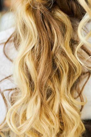 Blond curly female hair. Close-up. Well-groomed hair. Fashion hairstyleの写真素材