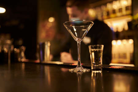 Martini glass and shot glass are on the bar.の写真素材