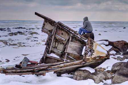 Shipwrecked  Teenaged male looking a frozen Lake Huron with wooden hull of a shipwreck in the foreground  Sanilac County Park  Lexington, Michigan  の写真素材