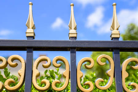 Intricate wrought iron fence and blue sky の写真素材