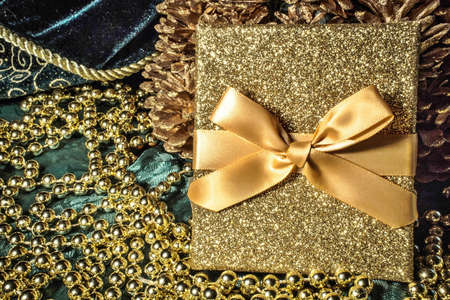 Christmas gift box with bow and surrounded by gold baubles.の写真素材