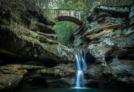 Waterfall with stone bridge crossing over the canyon. Hocking Hills State Park. Logan, Ohio.の写真素材