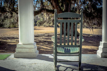 Southern Afternoon. Wooden rocker on a plantation style home with a Live Oak in the front yard.の写真素材
