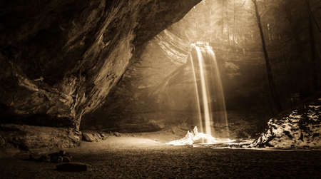 Mystical Forest Sunrise. Sunrise illuminates Ash Cave and the waterfall tumbling over the cliff precipice. Hocking Hills State Park. Logan, Ohio.の写真素材