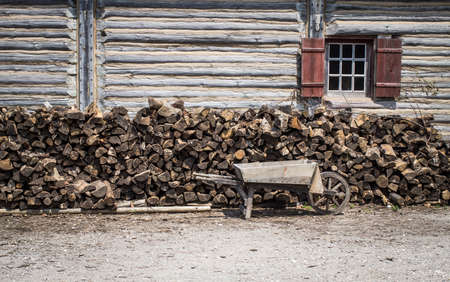 Ready For Winter.  Vintage wooden wheelbarrow and wood lined up on the exterior of a log cabin. This was taken at a state park and is not private property. It is located on public lands.の写真素材