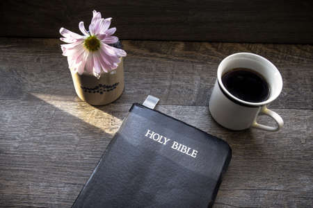 Morning Coffee With Bible Illuminated By Sunlight. Cup of coffee with Christian Bible illuminated by a ray of sun. Shot from above in natural light in horizontal orientation.の写真素材