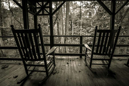 Two Wooden Rocks On Front Porch. Two wooden rocking chairs on an old front porch. Shot in black and white with horizontal orientation.の写真素材