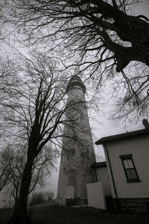Haunted Great Lakes Michigan Lighthouse. The reportedly haunted Pt. Aux Barques Lighthouse on the remote shores of Lake Huron surrounded by bare trees in vertical orientation. Port Hope, Michigan.の写真素材