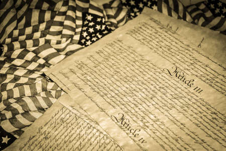 American Flag And US Constitution. Article III of the US Constitution surrounded by American Flags shot in horizontal orientation. Article III established the judicial branch of the US government.の写真素材