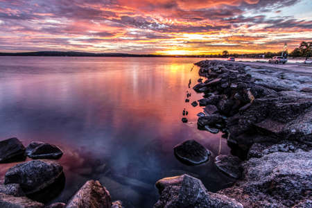 Downtown Traverse City Coastal Sunrise. Morning sunrise over the rocky coast of Grand Traverse Bay with downtown Traverse City, Michigan in the background.の写真素材
