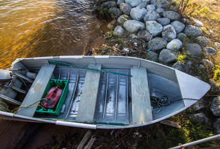 Small Fishing Boat On The Shore. Small aluminum rowboat with gas motor on the Great Lakes shore. Shot from above in horizontal orientation.の写真素材