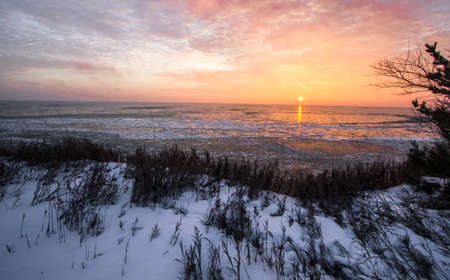Scenic Winter Sunrise Landscape. Scenic sunrise reflection over the icy Great Lakes horizon on the coast of Lake Huron from an overlook in Port Sanilac, Michigan.の写真素材