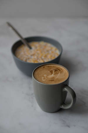 A cup of coffee and a bowl of cereals with milkの写真素材