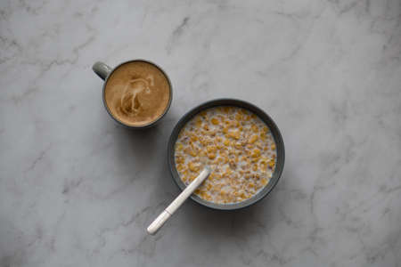 A cup of coffee and a bowl of cereals with milkの写真素材