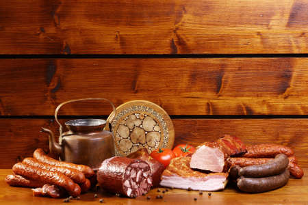 Rustic table with sausage and ham on a wooden backgroundの写真素材