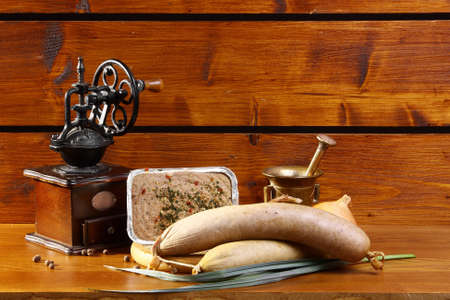 Liverwurst on a wooden table with a coffee grinder and mortarの写真素材