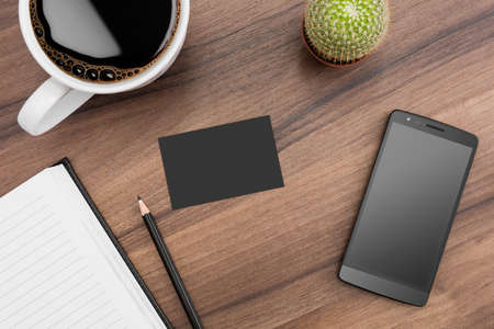 Brown desk with coffee, phone, notebook and cactusの写真素材