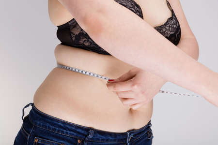 Overweight woman measuring her bellyの写真素材