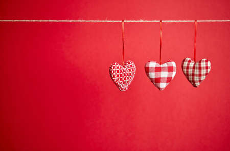 Three plush hearts on a red backgroundの写真素材
