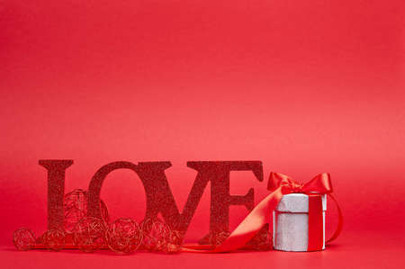 Red background with big glitter love sign and giftの写真素材