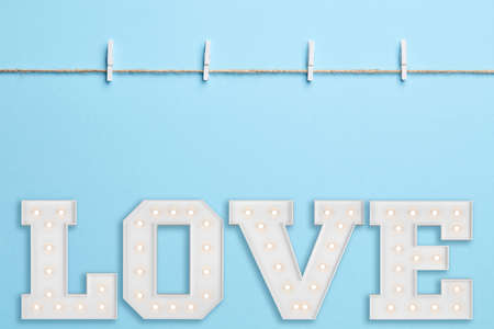 Blue background with empty sting, clothes peg and big illuminating loveの写真素材