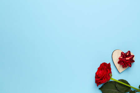Plain blue background with red rose and heart decorated with bowの写真素材