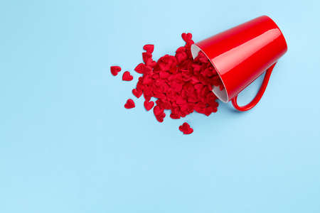 Plain blue background with composition of hearts spilling from red mugの写真素材