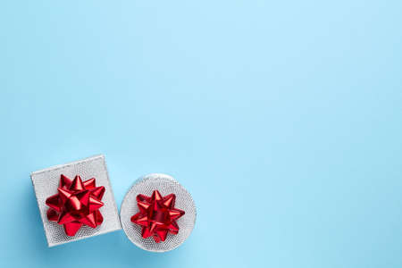 Blue plain background with silver gift and red ribbonの写真素材