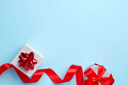 Blue plain background with silver gift and red ribbonの写真素材