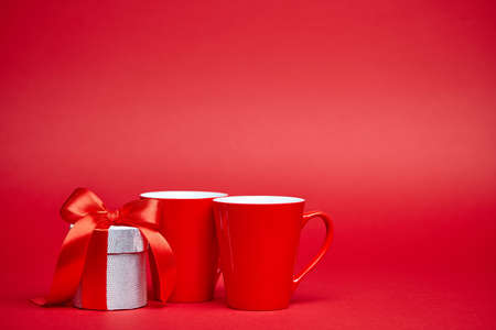 Red background with silver gift and two red cupsの写真素材