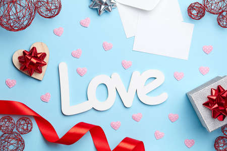 Blue plain background with silver gift, red ribbon, white love letter and signの写真素材