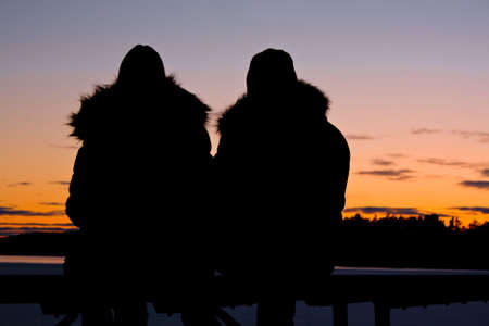 silhouettes of romantic couple watching the sunset の写真素材