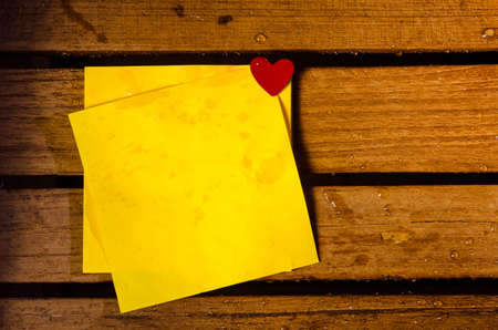 yellow blank paper with little red heart on wood pettern background の写真素材
