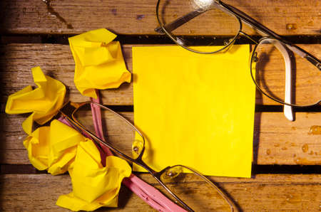 yellow blank paper with crumpled paper with two glasses on wood pettern background の写真素材