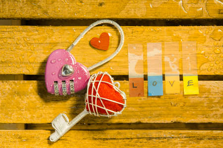 Pink master key with red heart key and love alphabet on wood pattern backgroundの写真素材