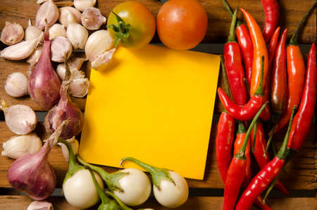 Yellow note with chilli,tomato,shallot and garlic on wood backgroundの写真素材
