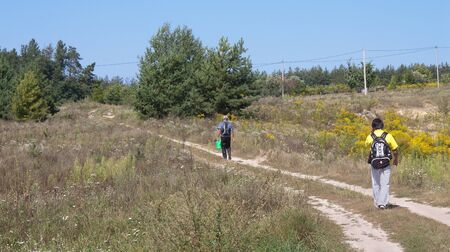 Two men with backpacks on rural roadの写真素材