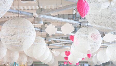 Many white lanterns  and hearts hanging in shopping mallの写真素材
