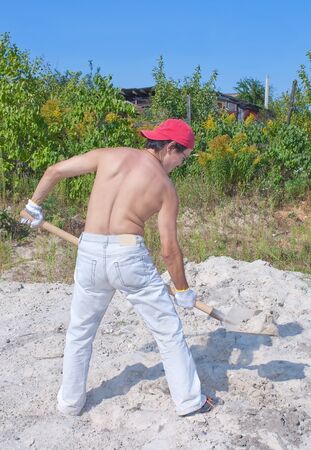 man's back with shovel in gardenの写真素材