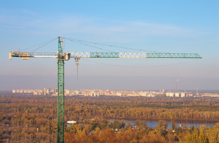 Construction crane against the blue sky and city housesの写真素材