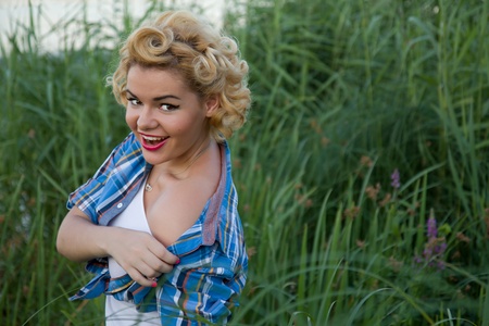 Young blond pinup female taking off her shirtの写真素材