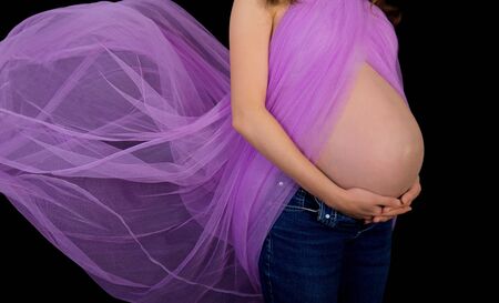 Beautiful pregnant woman with purple blowing fabricの写真素材