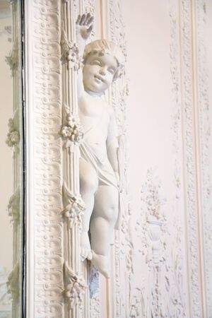 an ornate mirror and white wall with Cupid sculpture 
