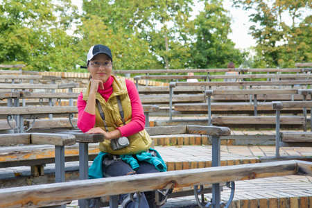 Beautiful asian tourist woman sitting on a bench at the green theatreの写真素材